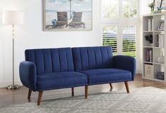 a blue couch sitting on top of a wooden floor next to a book shelf filled with books