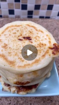 a stack of pancakes sitting on top of a blue plate next to a tiled wall