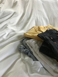 jeans folded on white bed Outfit Layed Out On Bed, Outfit On Bed Aesthetic, Clothes Folded Aesthetic, Clothes Laid Out On Bed Aesthetic, Clothes On Bed Aesthetic, Clothing Pile Aesthetic, Clothes Pile Aesthetic, Folded Clothes Aesthetic, Made Bed Aesthetic