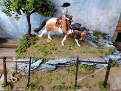 a statue of a man riding on the back of a brown and white horse next to a tree