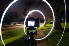 a camera is shown in front of a circular light on a tripod at night