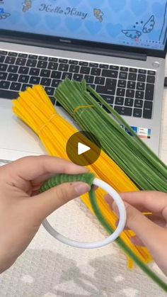 someone is holding some yellow and green noodles in front of a laptop