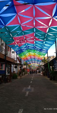 an empty street with many colorful umbrellas hanging from the ceiling