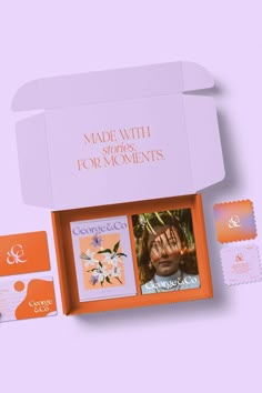 an orange and white box with some items inside it on a pink background, including two books