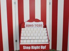 a red and white striped wall with a sign that says ring toss step right up