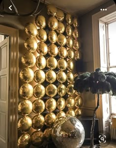 a room filled with lots of shiny gold balls on the wall next to a potted plant