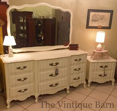 a white dresser with a mirror on top of it next to two lamps and a lamp