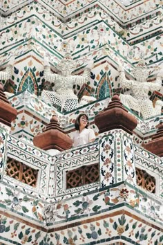 a woman standing on the balcony of a building with intricately painted walls and windows