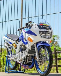 a white and blue motorcycle parked next to a fence