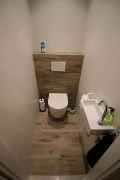 a bathroom with a toilet, sink and wooden paneled wall in it's corner