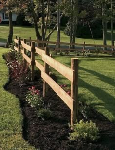 a wooden fence in the middle of a grassy area with flowers and trees around it