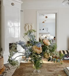 a vase filled with flowers sitting on top of a wooden table in front of a mirror