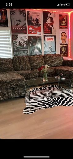 a living room with zebra print rugs and posters on the wall behind the couch