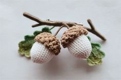 two crocheted acorns on a branch with leaves