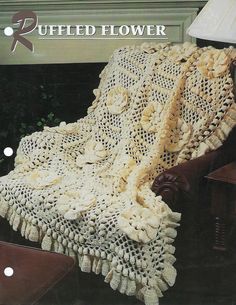 an old fashioned crocheted blanket sitting on top of a chair next to a lamp