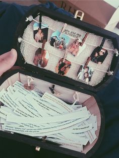 a person holding an open suitcase filled with pictures and letters on it's lid