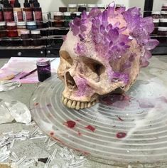 a skull with purple crystals sitting on top of a metal plate in front of bottles