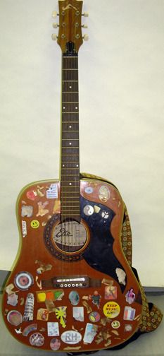 an acoustic guitar with many stickers on it