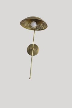 a brass plated wall light with a white ball on it's end and a metal pole in the middle