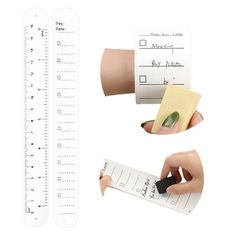 a hand holding a ruler with two pieces of paper attached to it