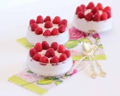 three small desserts with raspberries on top are sitting next to each other