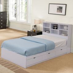 a white bed with blue sheets and drawers