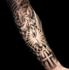 a man's arm with a cross and dove tattoo on the left side of his arm