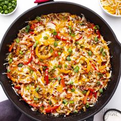 a skillet filled with vegetables and cheese on top of a white table next to other dishes