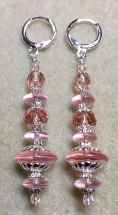 two pairs of pink and clear glass beaded earrings on a white surface with silver rings