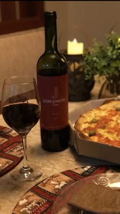 a bottle of wine sitting next to a pizza on top of a table