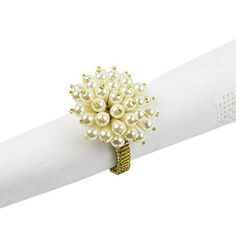 a napkin holder with pearls on it and a ring in the shape of a flower