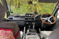 the interior of a vehicle with steering wheel and dash board, dashboard, and seats