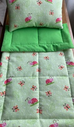 a bed with green sheets and pink ladybugs on the coverlet, along with matching pillow cases