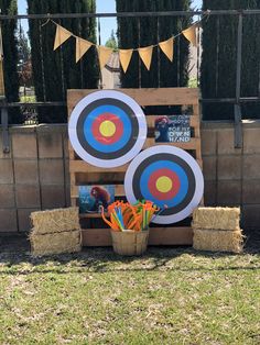 an outdoor area with hay bales and archery target decorations on display in front of a fence