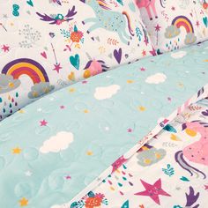 a bed with unicorns, stars and clouds on the sheet set in pastel colors