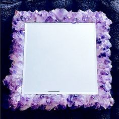 a mirror that is sitting on the ground with purple crystals around it and a white sheet in front of it