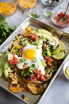 a tray filled with potato wedges topped with an egg and guacamole