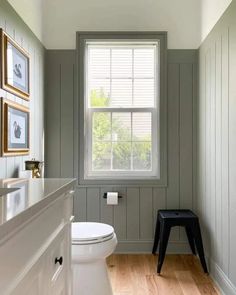 a white toilet sitting next to a window in a bathroom on top of a hard wood floor