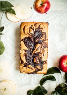 an apple and cinnamon swirl bread is on the table next to some apples with leaves