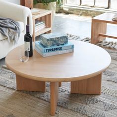 a coffee table with two books and a wine glass on it in front of a couch