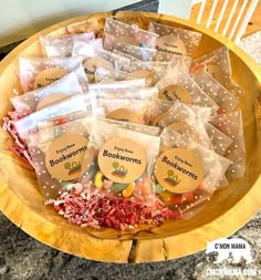 a wooden bowl filled with lots of bags of booksworms on top of a table