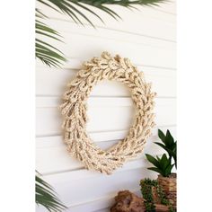 a wreath hanging on the wall next to some plants