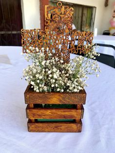 a wooden box with flowers in it sitting on a white table cloth covered tablecloth