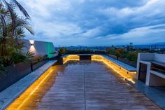 an outdoor patio with lights on the side and plants in the backgrounge