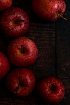 some red apples are sitting on a wooden table