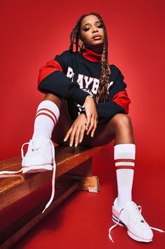 a woman sitting on top of a wooden bench wearing white tennis shoes and red socks