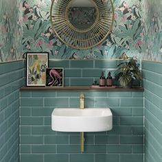 a green tiled bathroom with a sink, mirror and pictures on the wall above it