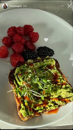 an avocado toast with berries and raspberries on the side