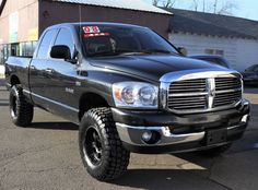 a black dodge ram truck parked in front of a building with a for sale sign on it