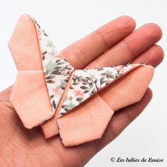 a hand holding an origami bow in it's palm